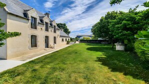 A large house with a well-maintained lawn, a stone pathway, and a stone wall.