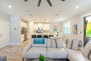 A modern living room with a sofa, a coffee table, and a kitchen in the background. - Lovely 4-bedroom Pool house in vibrant Tampa (Tampa)