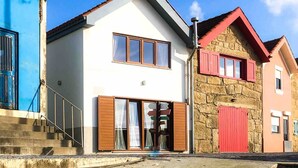 Un edificio moderno de dos pisos, con fachada blanca, techo rojo y pared de piedra.