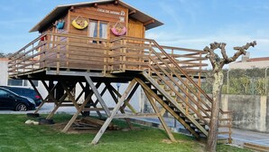 A wooden treehouse with a staircase, a car, and a clear sky. - Ninho do Carriço - Beach 200m away - Patio & KidsZone (Vila Chã)