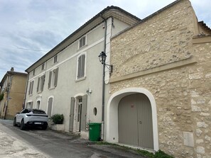 Ein Gebäude mit einer steinernen Fassade, einem großen Bogenportal und einem weißen geparkten Auto.