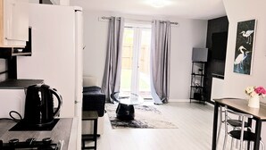 A modern kitchen with a stove, kettle, and dining area with a table and chairs. - Modern 2BR 5minutes walk Anfeild| Free parking+ Ev (Liverpool)