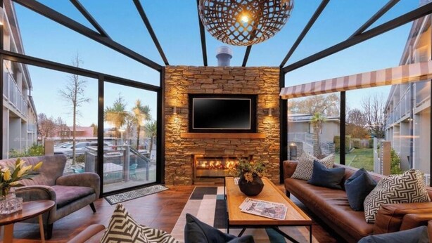 A modern living room with a stone fireplace, a flat-screen TV, and comfortable seating.
