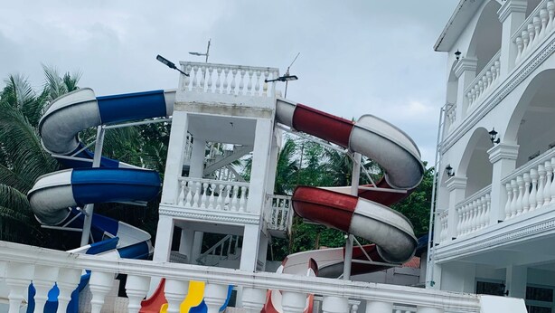 A water park with multiple slides and a white building with balconies. - Las casas resort dingalan (Dingalan)