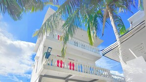 A multi-story building with balconies, palm trees, and a clear sky. - Las casas resort dingalan (Dingalan)