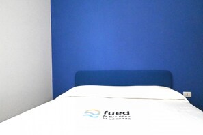A single bed with a white mattress and blue headboard in a room with blue walls. - P093 - Porto Recanati, new sea front apartment with a terrace (Porto Recanati)