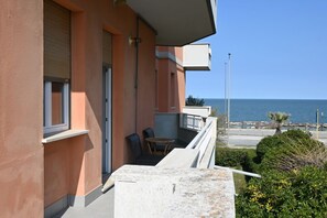 Ein Balkon mit Meerblick, einem Tisch mit Stühlen und einer kleinen Gartenanlage.