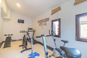 A gym with exercise equipment, a television, and a window with a view.