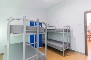 Bunk beds with storage compartments, a blue cabinet, and a door leading to a room with a table and chairs.