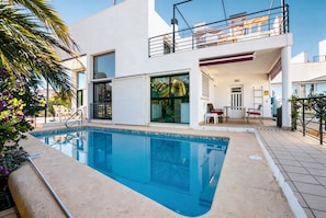A modern building with a swimming pool, large windows, and outdoor seating.