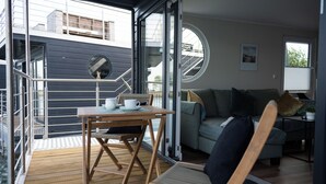 A modern interior with a wooden deck, a sofa, a table with a cup and saucer, and a staircase leading to an upper level.