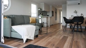 A modern living room with a sofa, a coffee table, and a dining area with chairs.