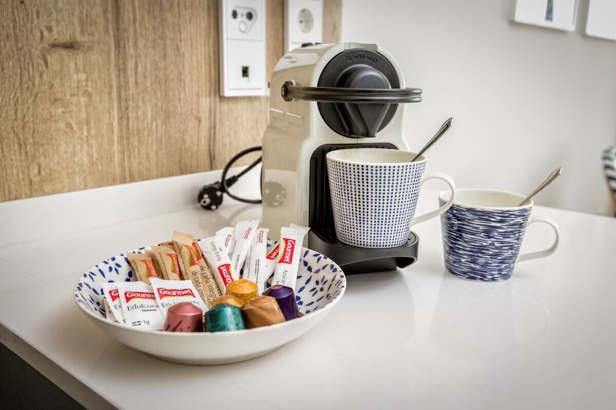 A kitchen counter with a coffee maker, a bowl of assorted chocolates, and a patterned mug.