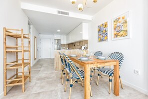 Una cucina moderna con mobili bianchi, un tavolo da pranzo in legno e sedie a righe blu.