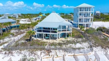 Una propiedad frente a la playa con una casa grande y una torre separada, ambas con varios niveles y balcones.