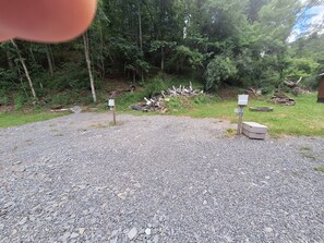 Un camino de grava conduce a una cabaña de madera rodeada de un bosque denso.