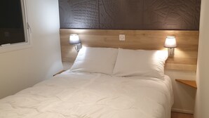 Ein Bett mit weißer Bettwäsche, zwei Nachttischlampen und einem Holzkopfende.