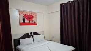 A neatly made bed with white linens, a dark wooden headboard, and a red and black artwork on the wall.
