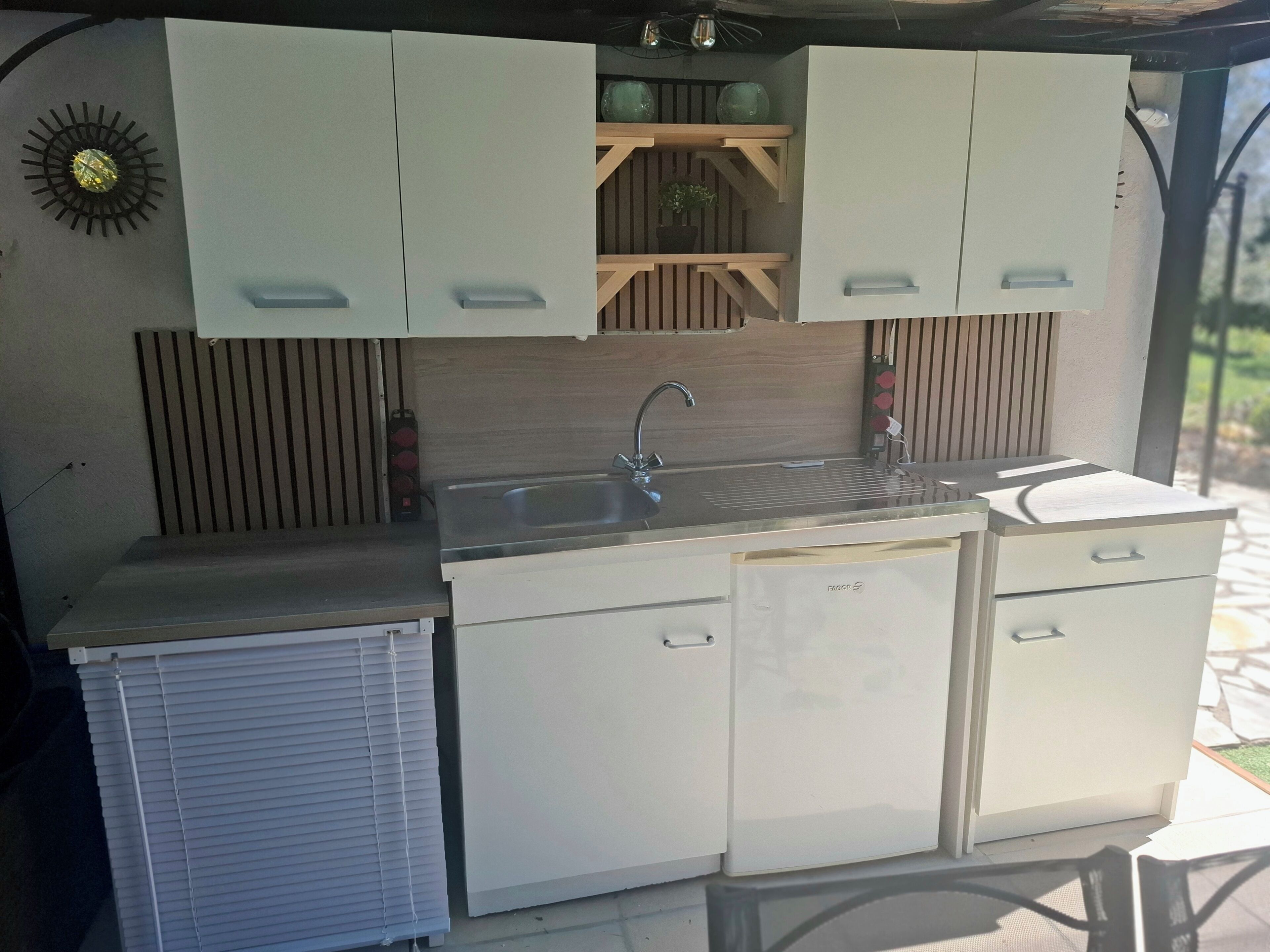 A compact kitchen with a sink, cabinets, and a built-in heater.