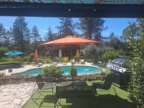 Un jardin avec une piscine, du mobilier d’extérieur et un barbecue.