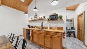 Una cocina con armarios de madera, un microondas negro y lámparas colgantes.