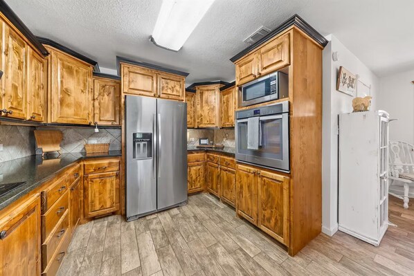 A kitchen with wooden cabinets, stainless steel appliances, and a white refrigerator. - Secluded Lodge Retreat Near Broken Bow (Lockesburg)