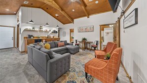 Amplia sala de estar con sofá modular, mesa de comedor y cocina al fondo.
