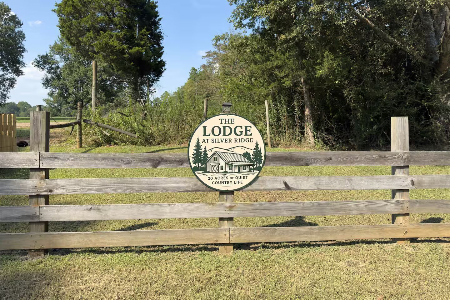 Et træhegn med et skilt, der står 'The Lodge at Silver Ridge' og nævner '20 tønderland af stille landlig tilværelse'.