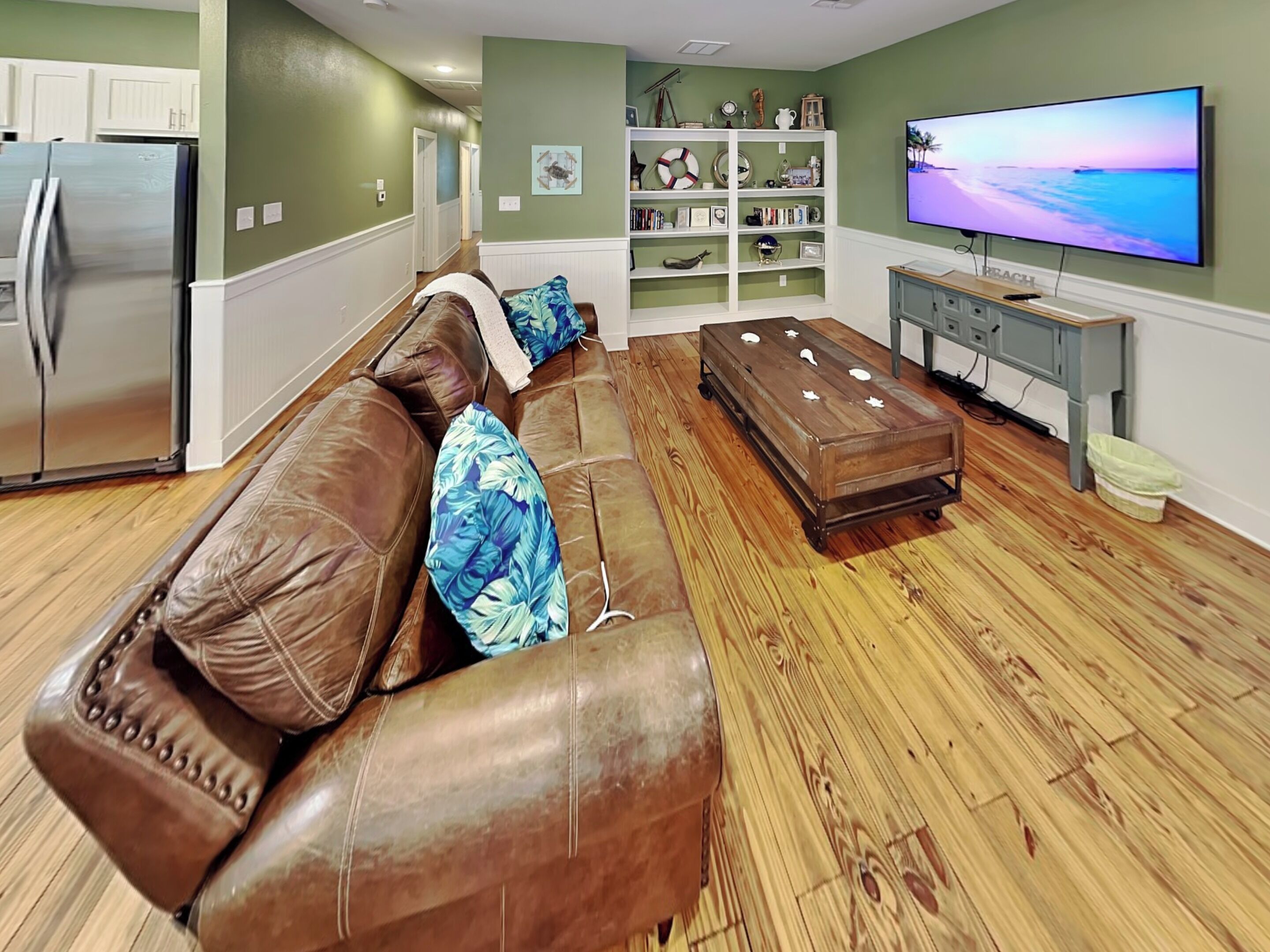 Een woonkamer met een leren bank, een houten salontafel en een televisie op een dressoir.