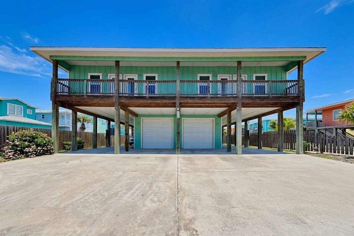 A two-story house with a balcony, a garage, and a concrete driveway.