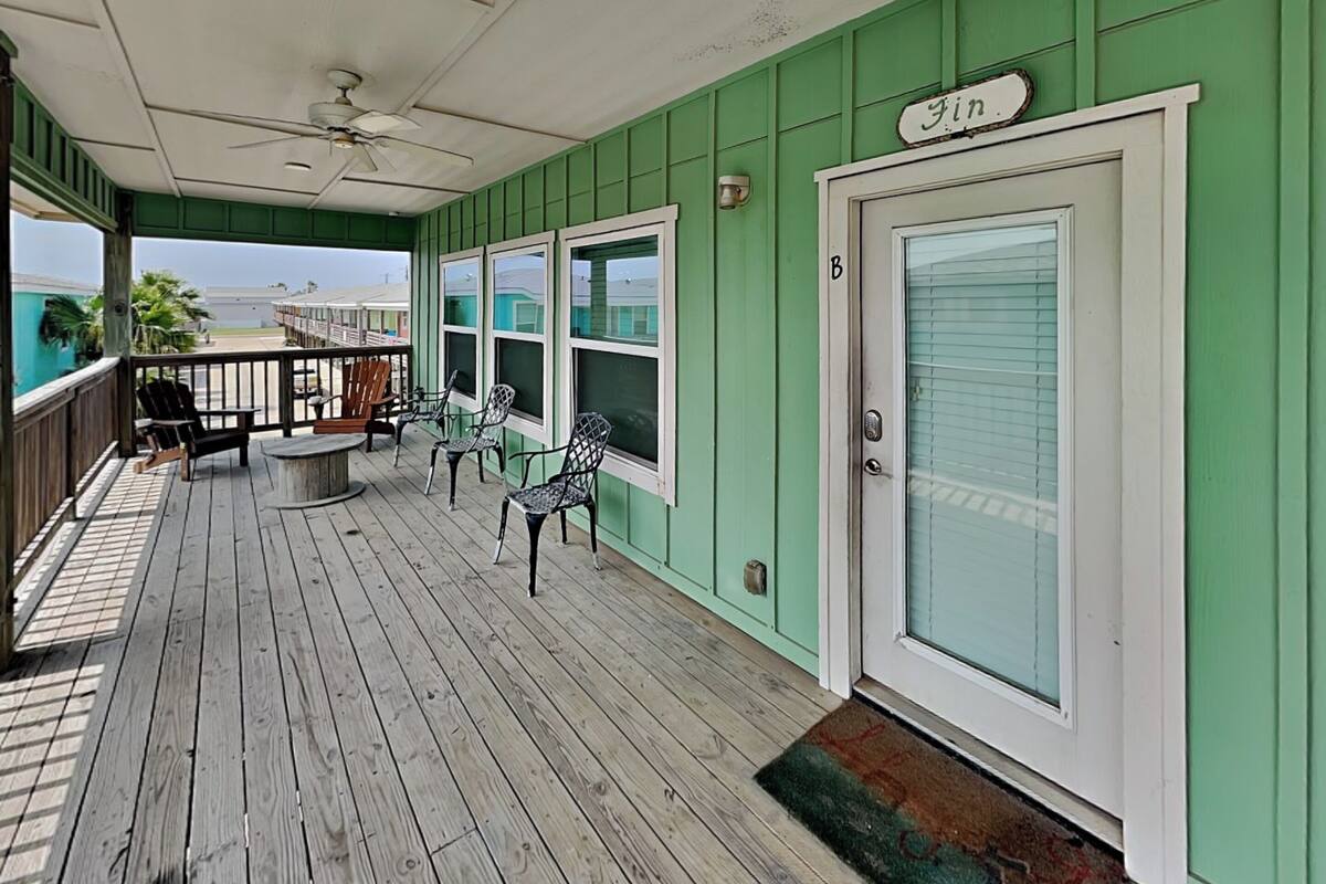 A covered porch with wooden flooring, a ceiling fan, and a door labeled 'Fin'.