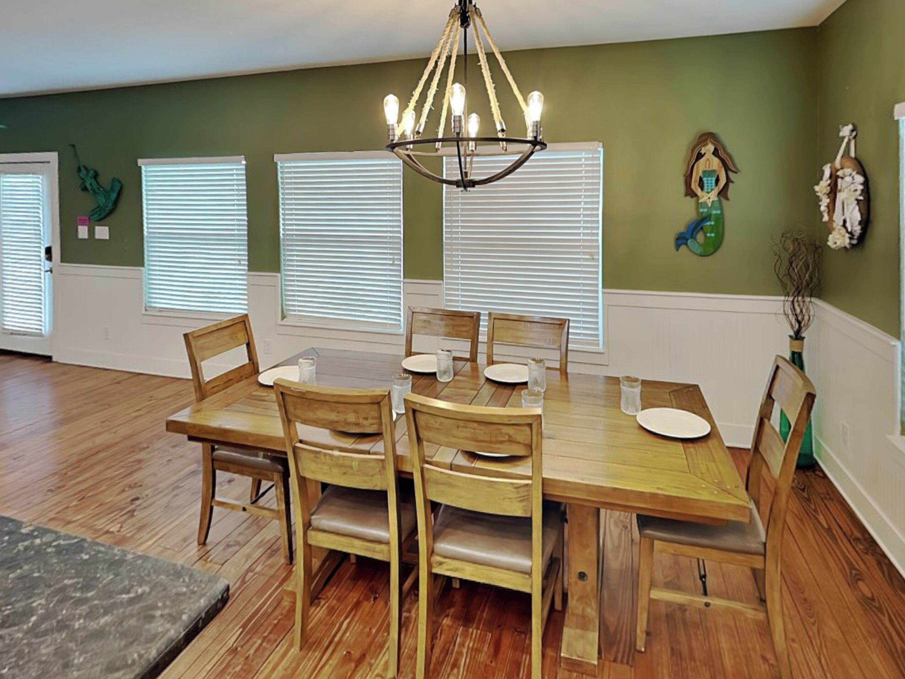 A dining area with a wooden table and chairs, a chandelier, and decorative wall art.