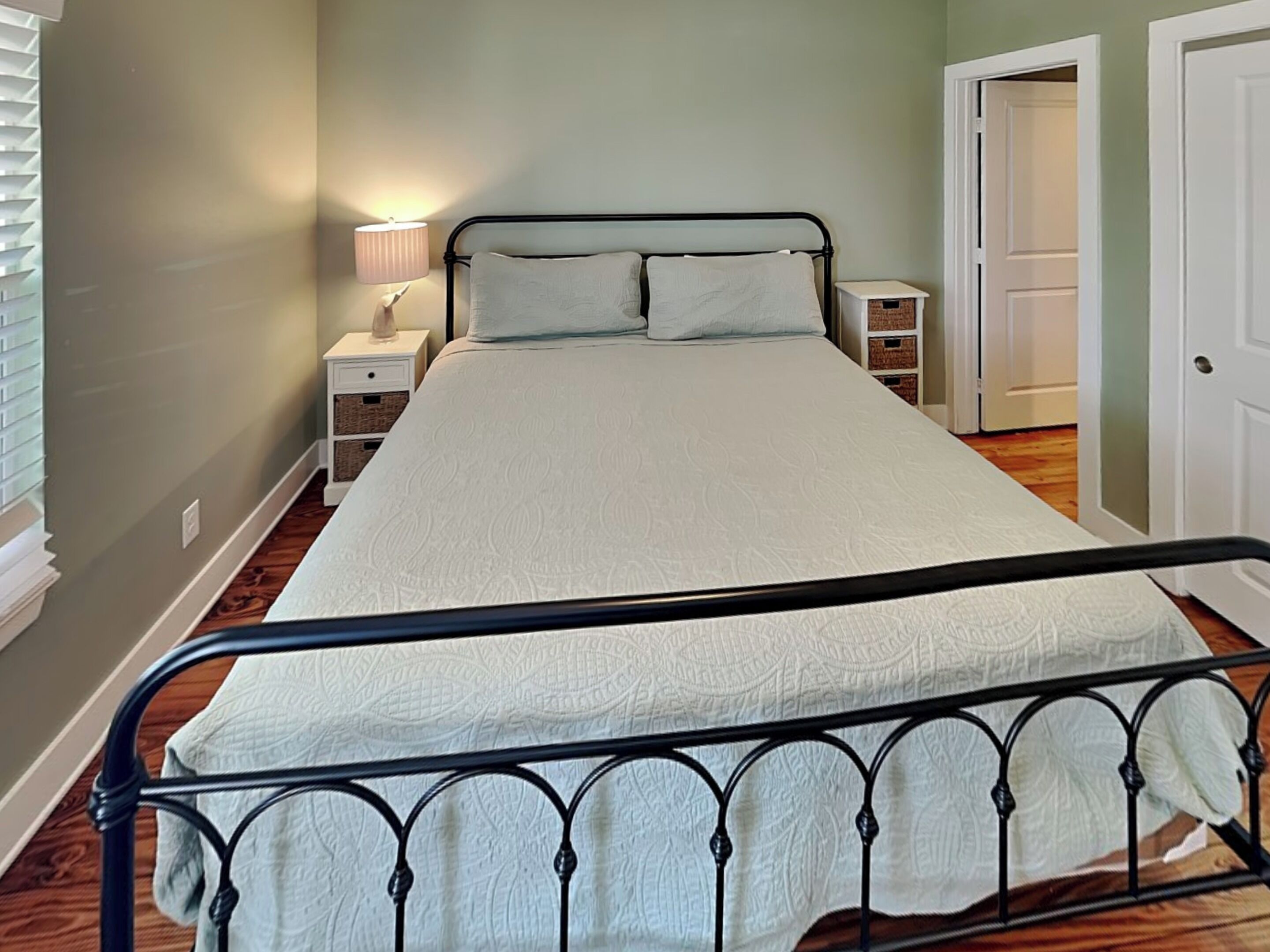 Una camera da letto con un letto, comodini, una lampada e cesti portaoggetti.