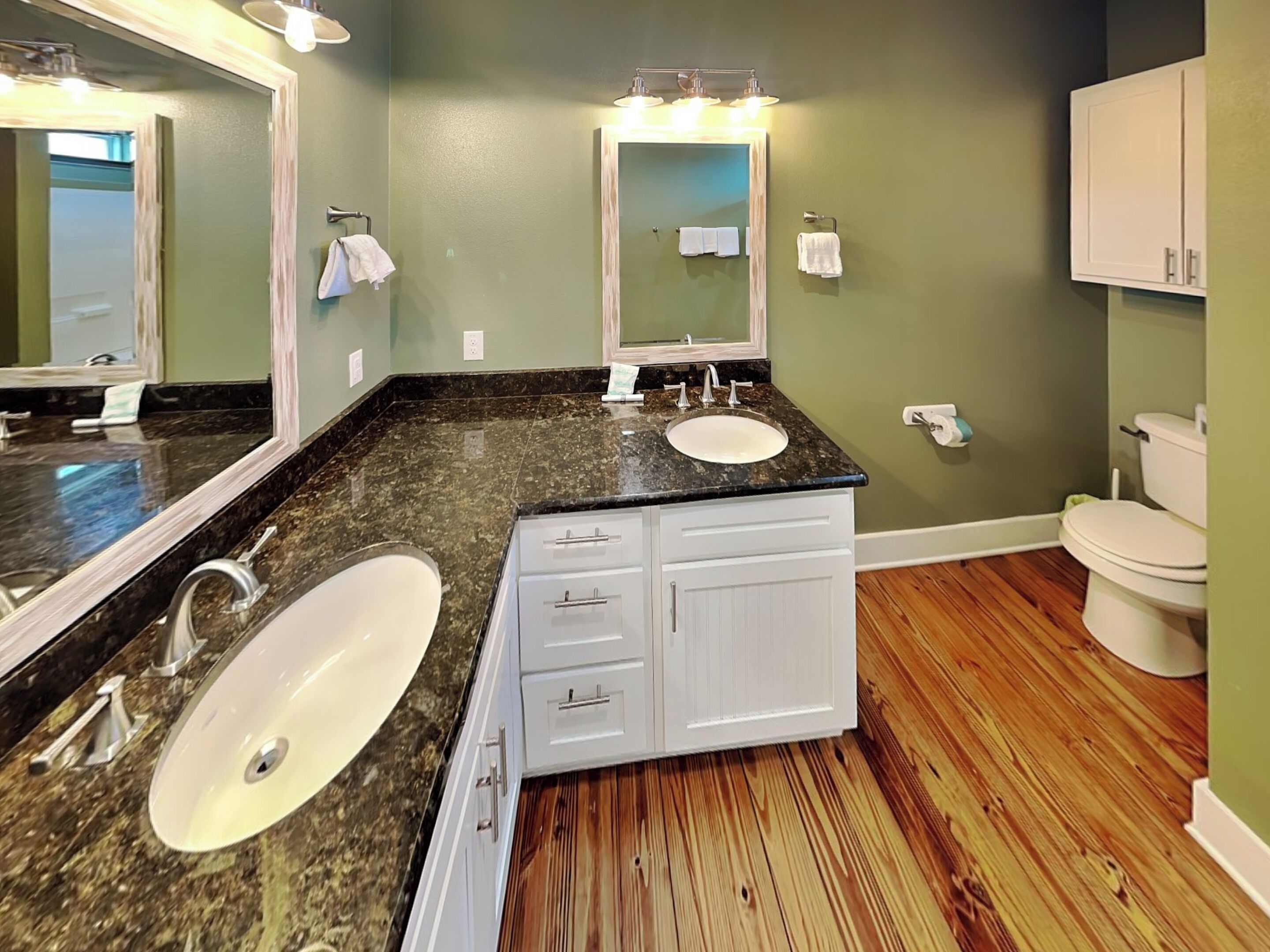 Une salle de bain avec un double lavabo, un meuble-lavabo, un miroir et des toilettes.