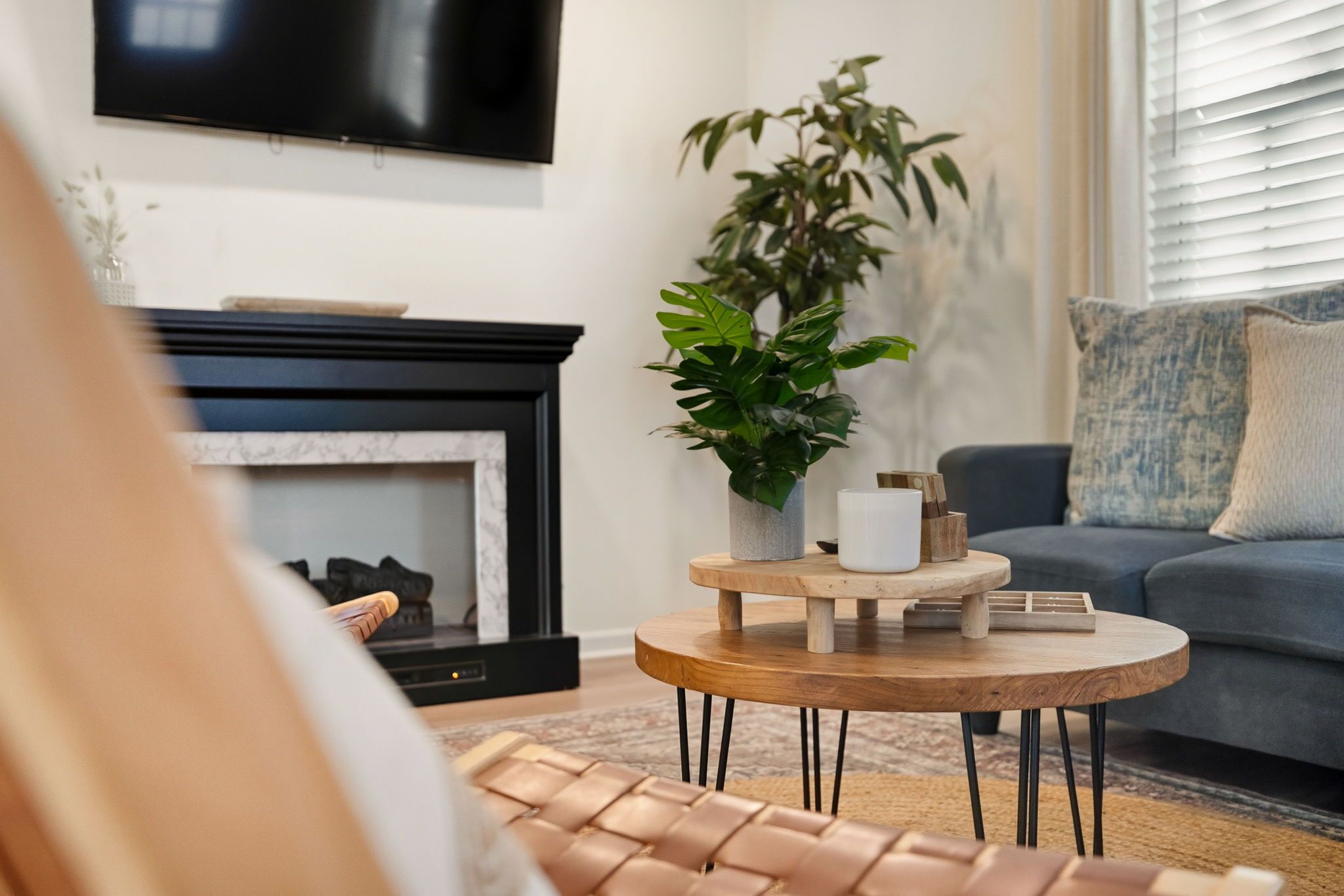 A living room with a fireplace, a television mounted on the wall, a sofa, and a coffee table with a plant and decorative items.