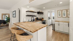 Una cocina moderna con una isla de madera, armarios blancos y un cartel que dice 'Beach'.
