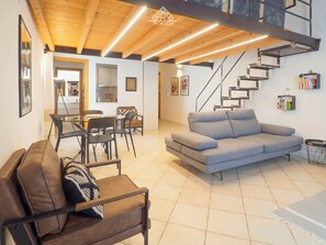 Una sala moderna con sofá, sillas, comedor y una escalera.