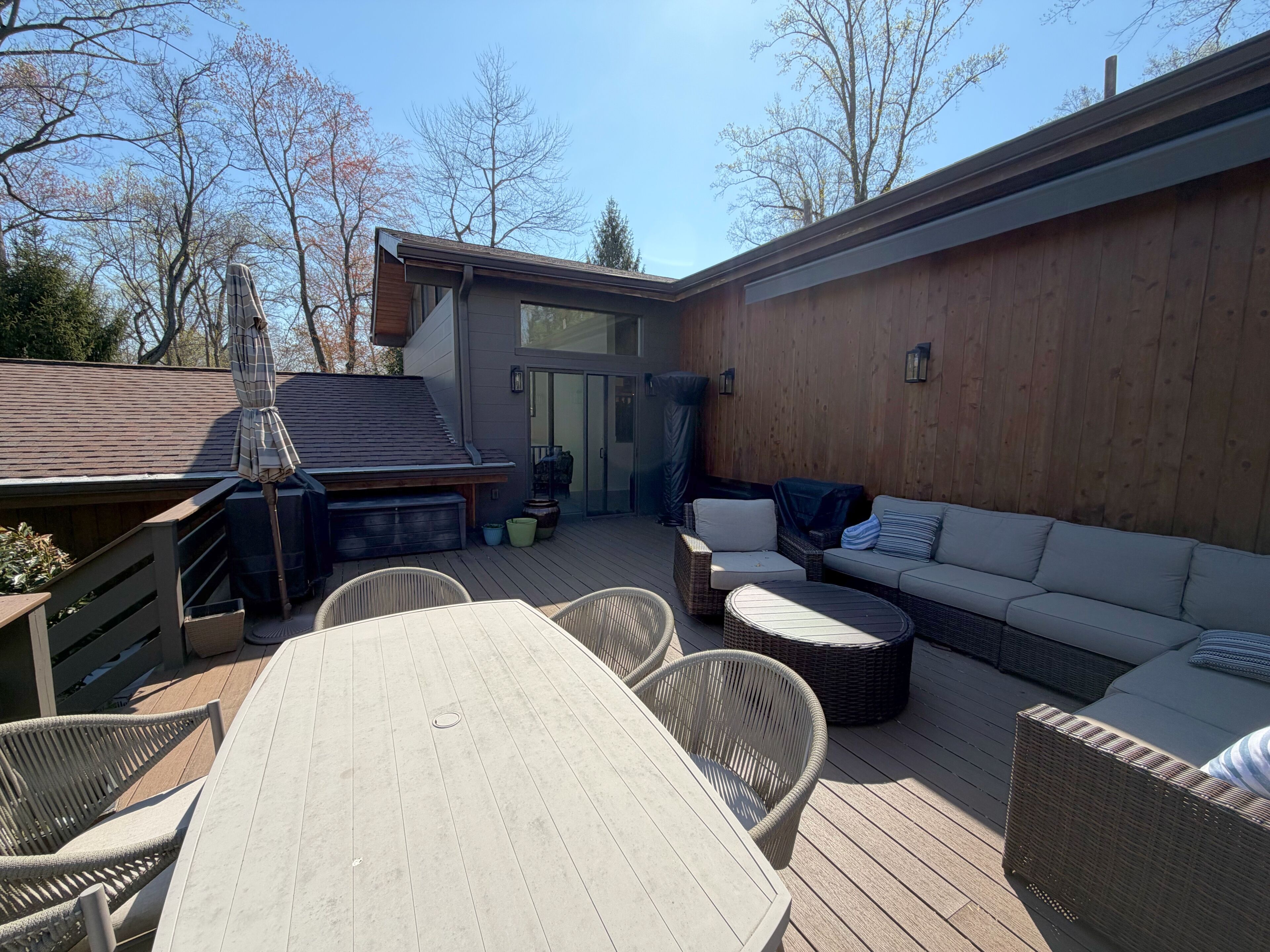 Un patio exterior techado con una mesa de comedor, sillas, un sofá y una parrilla.