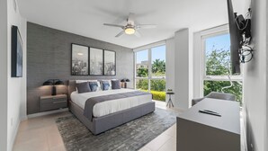 A modern bedroom with a large bed, a desk, a ceiling fan, and a cityscape view through the window. - 2 Bed/3 Bath Beach Townhouse  I 1600sqft I 5 Star amenities I No Resort fee I (Fort Lauderdale)