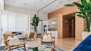 A modern hotel lobby with wicker chairs, a marble coffee table, and a large potted plant. - 2 Bed/3 Bath Beach Townhouse  I 1600sqft I 5 Star amenities I No Resort fee I (Fort Lauderdale)