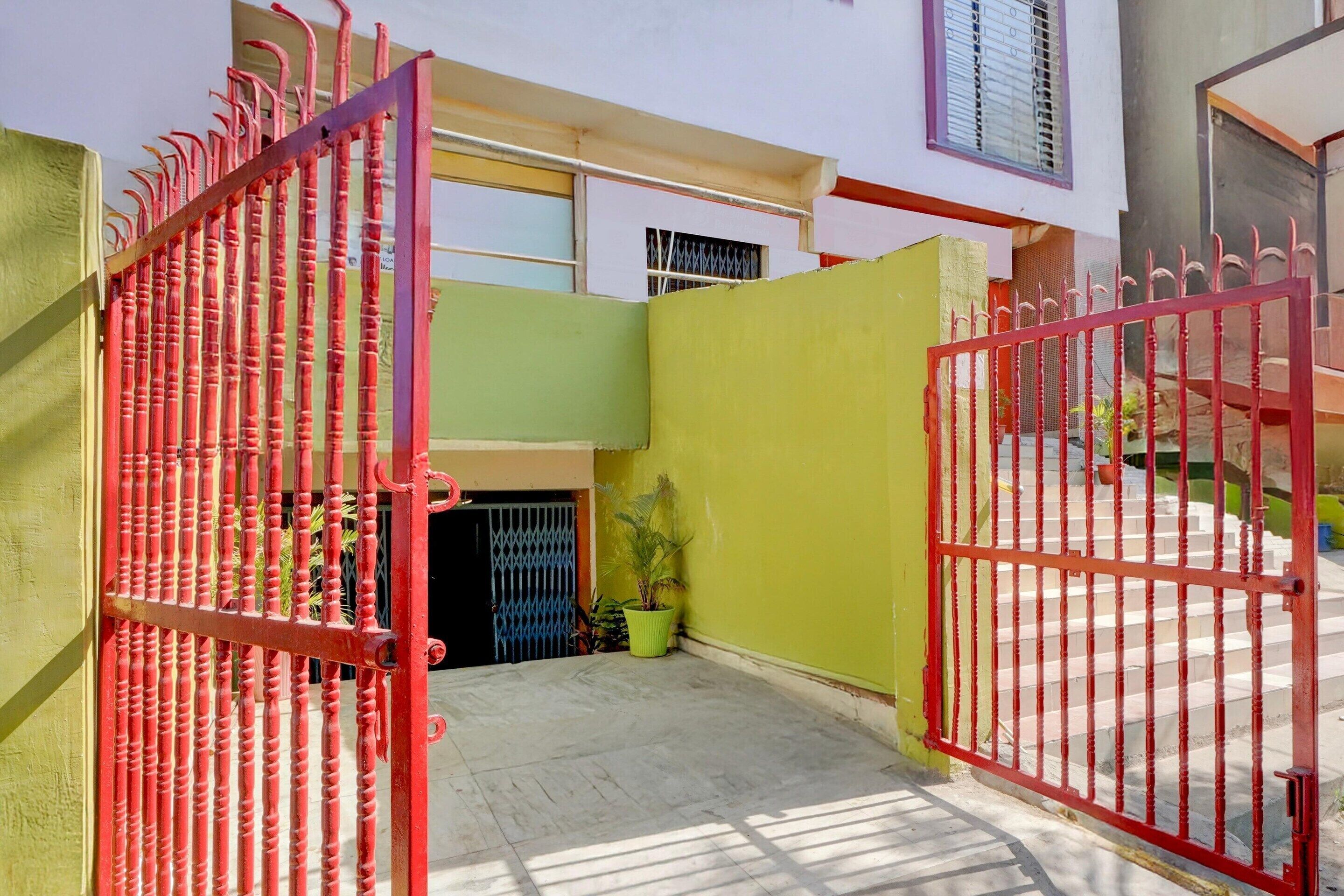 A gated courtyard with a potted plant, a metal gate, and a building with a window.