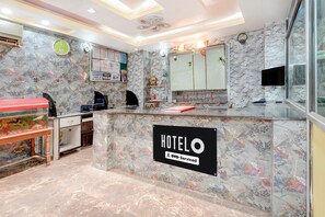 A hotel reception area with a marble counter, a clock, and a notice board.