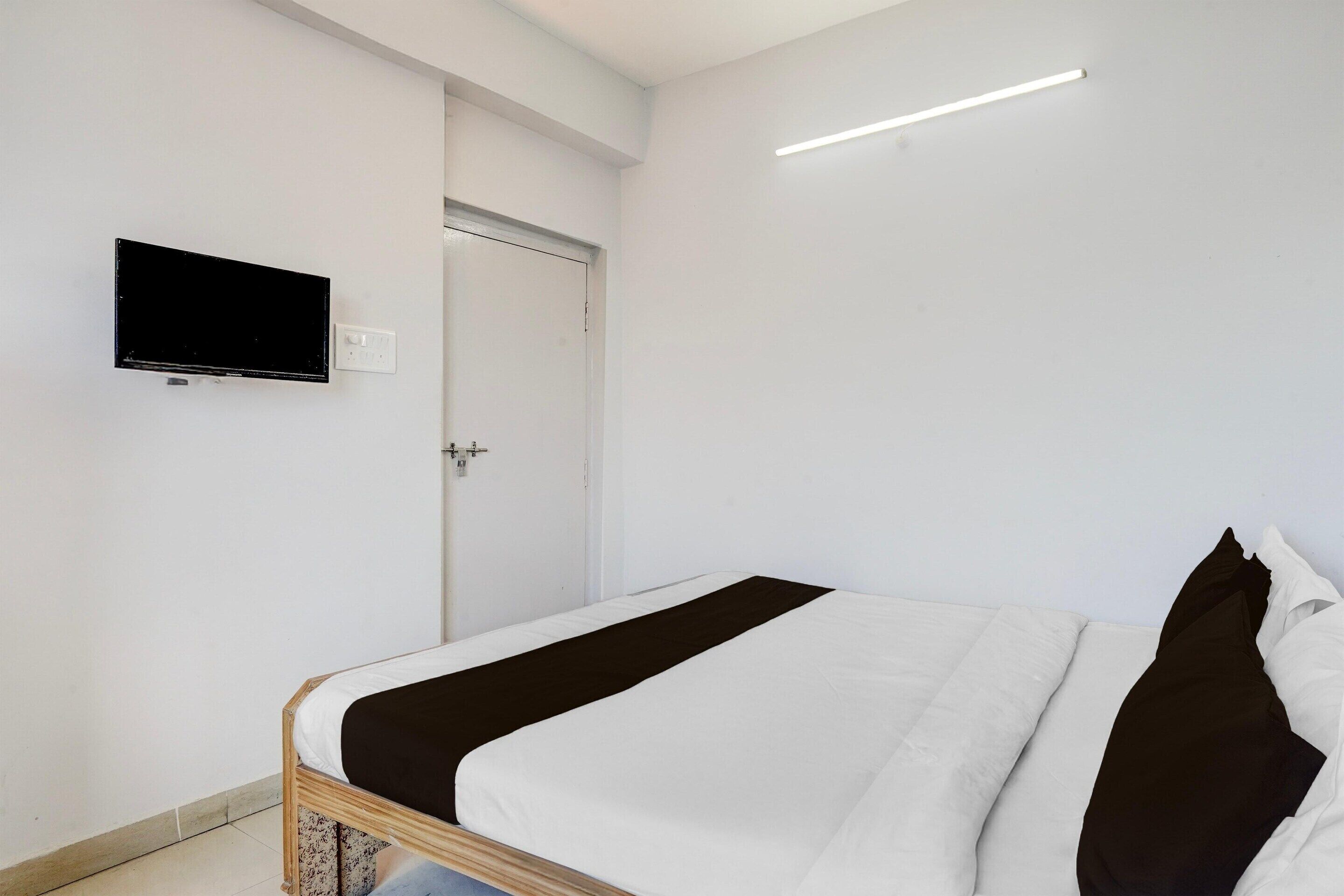 A bedroom with a bed, a television mounted on the wall, and a door.