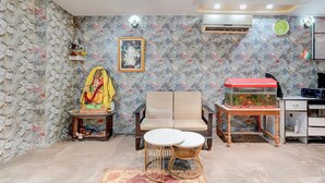 A room with a sofa, a small table, a fish tank, and a statue. - Classic Hotel Four Square (Patna)