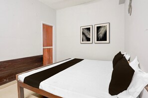Une chambre à coucher avec un lit, un banc en bois et deux œuvres d’art représentant des feuilles, encadrées et accrochées au mur.