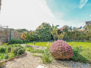 A garden with a variety of plants and a stone wall. - 2 Trelawny Way (Bembridge)