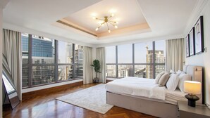 Ein geräumiges Schlafzimmer mit einem großen Bett, einer modernen Chandelier und Blick auf die Stadt.