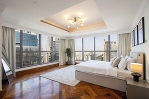 Ein geräumiges Schlafzimmer mit einem großen Bett, einer modernen Chandelier und Blick auf die Stadt.