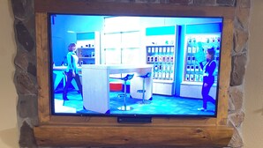 Een televisie bevestigd aan een stenen muur, onder een open haard.
