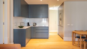 Eine moderne Küche mit grauen Schränken, einem Holztisch und einer Kücheninsel mit Spüle und Wasserkocher.